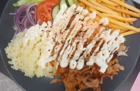 Plated chicken katsu drizzled with mayo, served with fries, coleslaw, tomato, and shredded cabbage