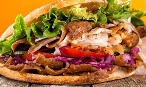 Gourmet sandwich on crusty bread with lettuce, bacon, white cheese, tomato and cabbage