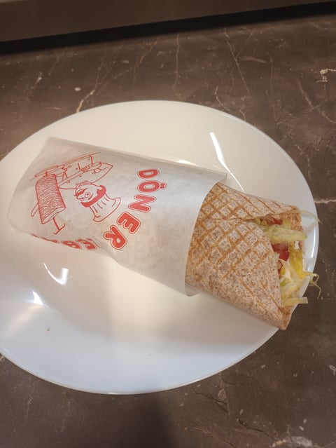 Wrapped sandwich with red text on paper wrapper next to unwrapped portion on white plate